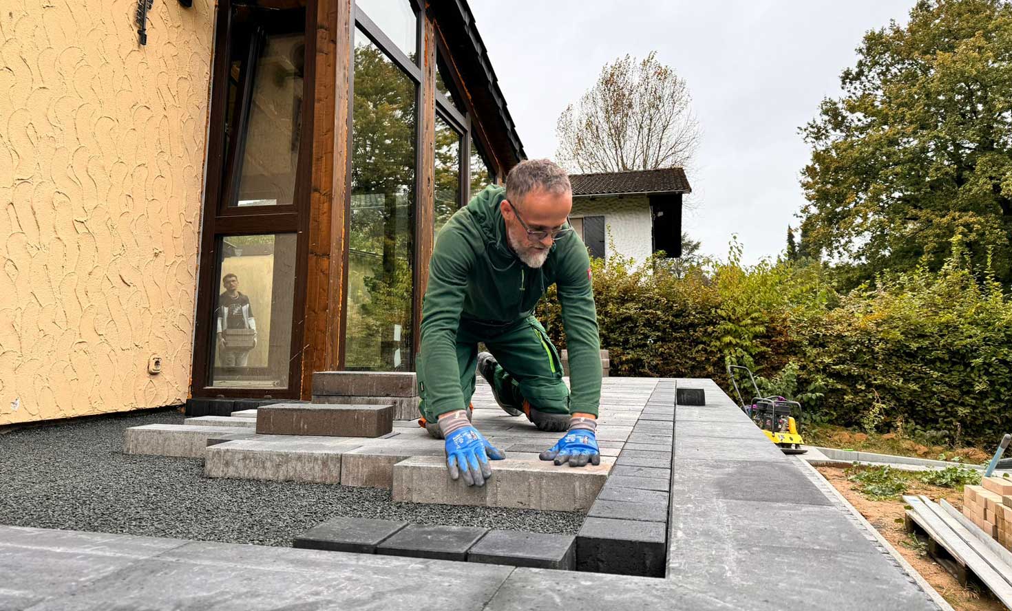 Erik Hitaj beim Verlegen von Pflastersteinen auf einer Terrasse in Mücke