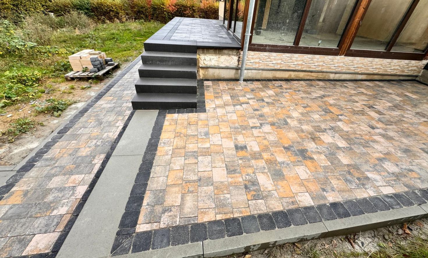 gepflasterte Terrassenanlage auf zwei Ebenen mit Treppenstufen und Gehweg in Mücke